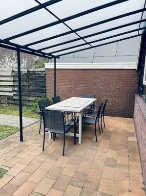 a patio with a table and chairs under a pergola at Leuke bungalow in Noord-Holland in Opmeer