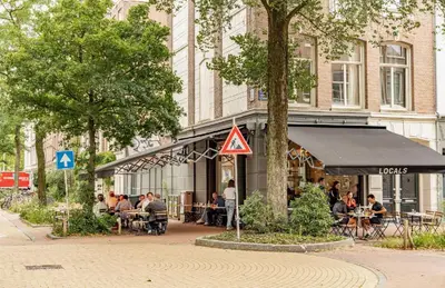 a group of people sitting at tables in front of a building at LIEV Amsterdam Cozy boutique suite in The Pijp in Amsterdam