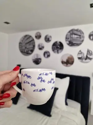 a person holding a coffee cup on a bed at LIEV Amsterdam Cozy boutique suite in The Pijp in Amsterdam