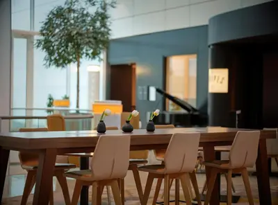 a wooden table with chairs and a table with vases on it at Sheraton Amsterdam Airport Hotel and Conference Center in Schiphol