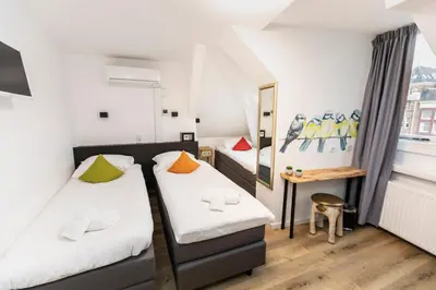 two beds in a room with a table and a mirror at Hotel Pagi in Amsterdam