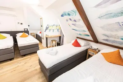 a room with three beds and a table in it at Hotel Pagi in Amsterdam