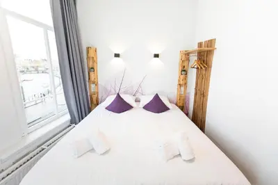 a bedroom with a bed with white sheets and purple pillows at Hotel Pagi in Amsterdam