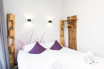 a bedroom with a white bed with purple pillows at Hotel Pagi in Amsterdam