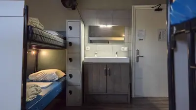 a small room with two bunk beds and a sink at Hostel Cosmos Amsterdam in Amsterdam
