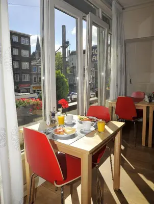a table with a plate of food and red chairs at Hotel Abba in Amsterdam