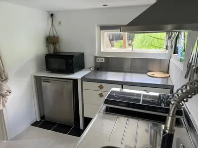 a small kitchen with a stove and a microwave at Huisje op de dijk in Kortenhoef