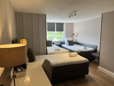 a hotel room with two beds and a lamp at Hotel Hermitage Amsterdam in Amsterdam