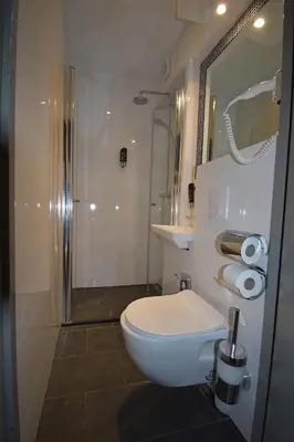 a bathroom with a white toilet and a shower at Hotel Hermitage Amsterdam in Amsterdam