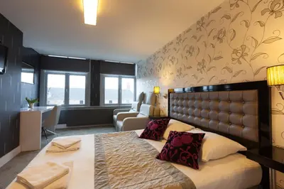 a bedroom with a bed and a living room at Hotel Hermitage Amsterdam in Amsterdam