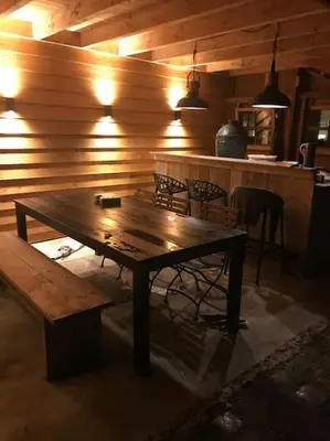 a wooden table and benches in a room with a bar at Farmvilla with hottub and outdoor kitchen in Beets