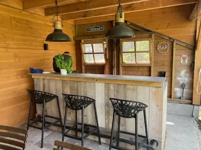 a bar in a cabin with three black stools at Farmvilla with hottub and outdoor kitchen in Beets