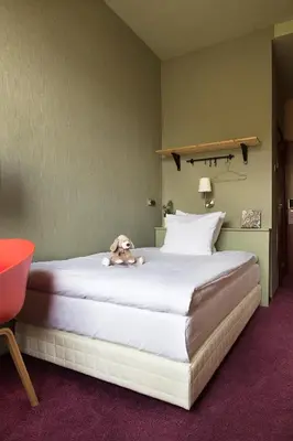 a stuffed dog laying on a bed in a hotel room at Hotel The Neighbour's Magnolia in Amsterdam