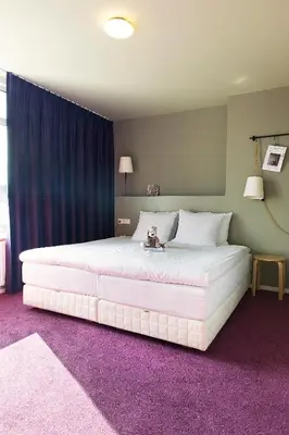 a large white bed with a teddy bear sitting on it at Hotel The Neighbour's Magnolia in Amsterdam