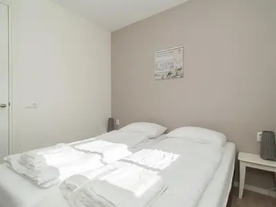a white bed with white sheets on it in a room at Holiday Home near Dutch Coast & Forest in Noordwijk