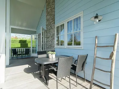 a patio with a table and chairs on a blue house at Holiday Home near Dutch Coast & Forest in Noordwijk