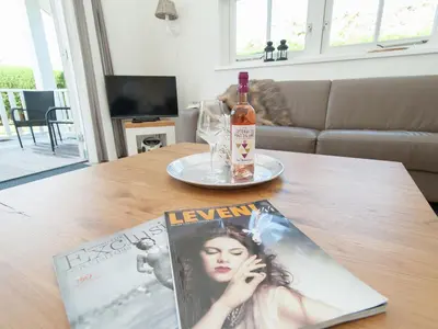 a magazine and a bottle of wine on a table at Holiday Home near Dutch Coast & Forest in Noordwijk