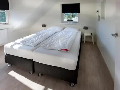 a bedroom with a large bed with white sheets at Holiday Home near Dutch Coast & Green Park in Noordwijk