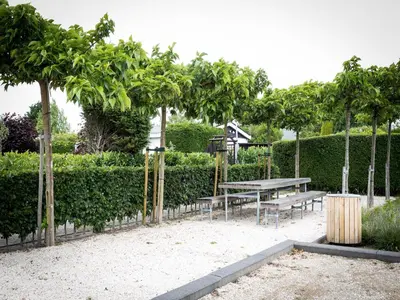 a picnic table and benches in a park with trees at Holiday Home near Dutch Coast & Green Park in Noordwijk