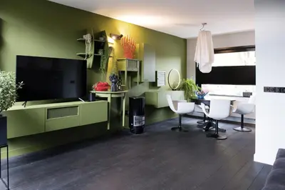 a living room with a television and a table and chairs at Bijzonder stadshuis met diepe moderne tuin. in Alphen aan den Rijn