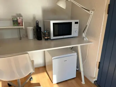 a white desk with a microwave and a desk with a chair at Zuidwest Zeven free parking! in Zandvoort