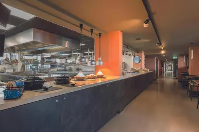 a large kitchen with a long counter in a restaurant at Leonardo Hotel IJmuiden Seaport Beach in IJmuiden