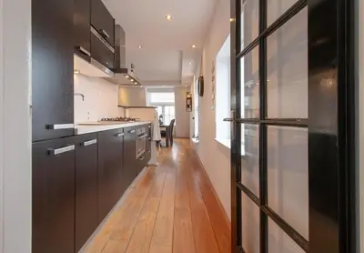 a kitchen with black cabinets and a wooden floor at ApartHotel Trendy by Urban Home Stay in Alkmaar