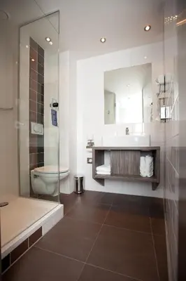 a bathroom with a sink and a toilet and a shower at WestCord City Centre Hotel in Amsterdam