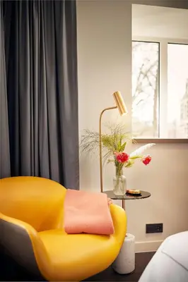 a yellow chair in a room with a window at Park Plaza Vondelpark Amsterdam in Amsterdam