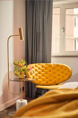 a bedroom with a yellow chair and a table with flowers at Park Plaza Vondelpark Amsterdam in Amsterdam