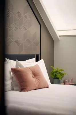 a bed with a pink pillow on top of it at Park Plaza Vondelpark Amsterdam in Amsterdam