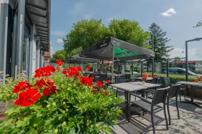 a table and chairs with red flowers in front of a building at Boutique Hotel Herbergh Amsterdam Airport FREE PARKING in Badhoevedorp
