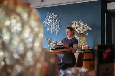 a woman sitting at a table in a restaurant at Boutique Hotel Herbergh Amsterdam Airport FREE PARKING in Badhoevedorp