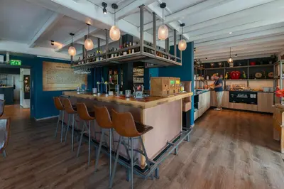 a bar in a restaurant with a man standing at a counter at Boutique Hotel Herbergh Amsterdam Airport FREE PARKING in Badhoevedorp