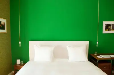 a green bedroom with a white bed and a green wall at Vesper Hotel in Noordwijk aan Zee