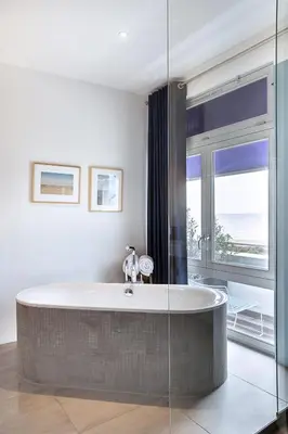 a bath tub in a bathroom with a large window at Vesper Hotel in Noordwijk aan Zee