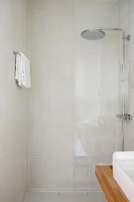 a shower with a glass door next to a sink at Vesper Hotel in Noordwijk aan Zee