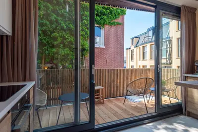a balcony with sliding glass doors and a table and chairs at The Modern Burrow in Zandvoort