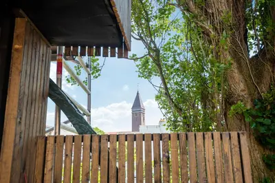 a wooden fence with a church tower in the background at The Modern Burrow in Zandvoort