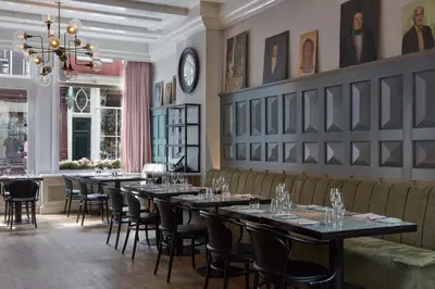 a restaurant with tables and chairs and a chandelier at Pulitzer Amsterdam in Amsterdam