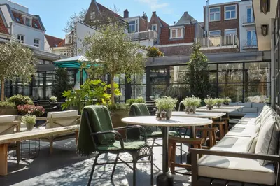 an outdoor patio with tables and chairs and trees at Pulitzer Amsterdam in Amsterdam