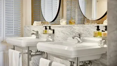 two sinks in a bathroom with mirrors and towels at Pulitzer Amsterdam in Amsterdam