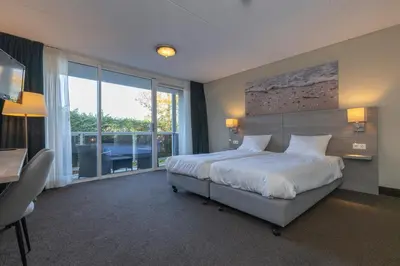 a bedroom with a large bed and a large window at Fletcher Hotel Jan van Scorel in Schoorl