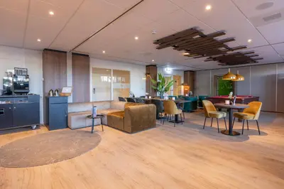 a lobby with chairs and tables in a room at Fletcher Hotel Jan van Scorel in Schoorl