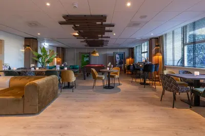 a restaurant with tables and chairs in a room at Fletcher Hotel Jan van Scorel in Schoorl