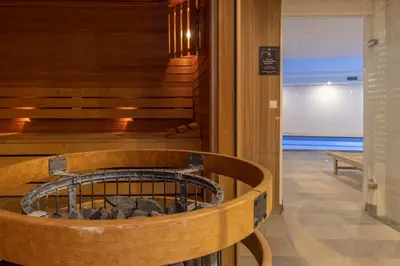 a wooden bench in a lobby with a fire pit at Fletcher Hotel Jan van Scorel in Schoorl