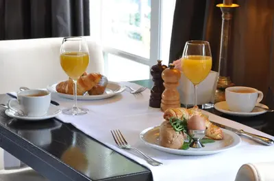 a table with plates of food and two glasses of orange juice at Fletcher Hotel Jan van Scorel in Schoorl
