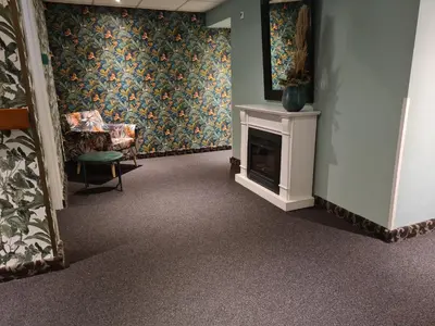 a waiting room with a fireplace and a chair at Amsterdam Hotel Uithoorn in Uithoorn