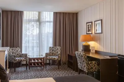 a hotel room with a desk and chairs and a window at Amsterdam Hotel Uithoorn in Uithoorn