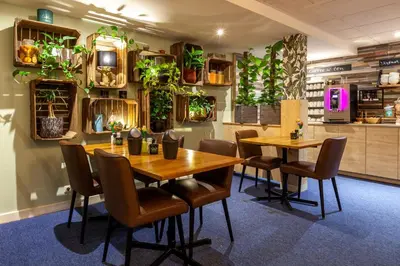 a restaurant with two tables and chairs and plants on the wall at Amsterdam Hotel Uithoorn in Uithoorn